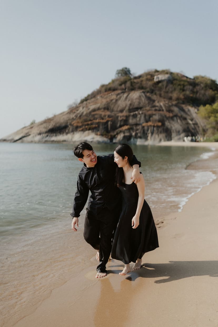 The couple walking up out of the waves, hands linked