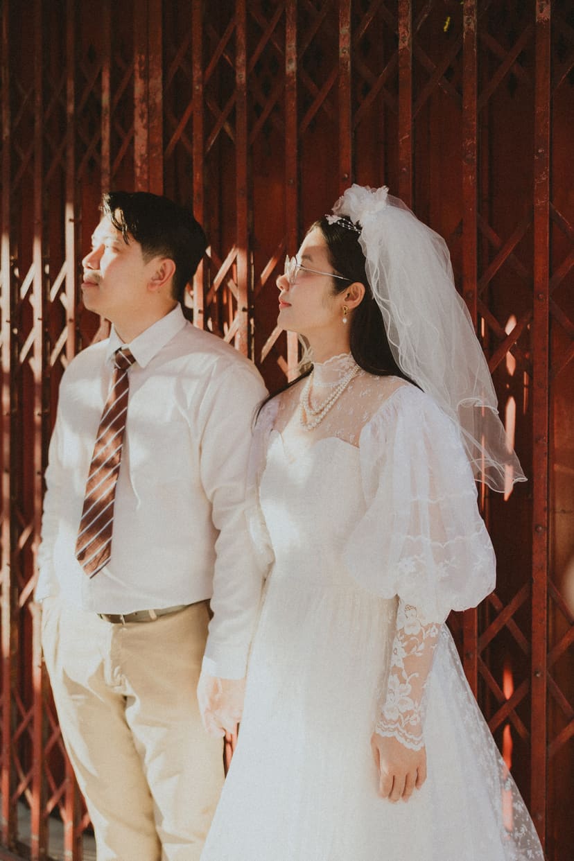 The couple in front of red shophouse shutters on Songwat Road