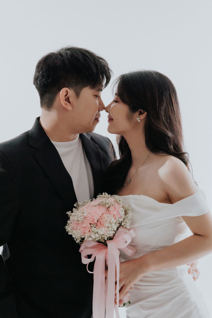 The couple close together with a bouquet in the studio